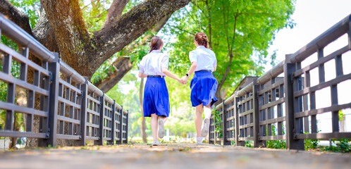 friendship schoolgirl in thai student secondary school uniform walk together outdoor in park