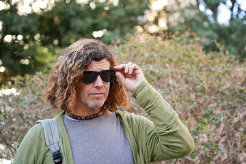 Man with sunglasses and curly hair trekking along a path