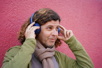 Man with curly long hair listening music with headphones
