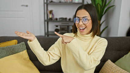 Hispanic woman smiling gesturing presentation living room glasses yellow sweater
