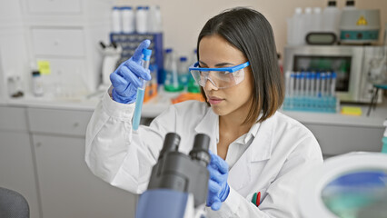A focused young woman scientist examines a test tube in a modern laboratory setting, conveying innovation and research.