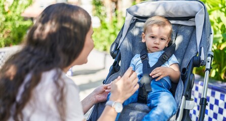 Mother and son smiling confident sitting on stroller baby at park