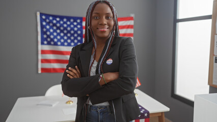 African american woman with braids, arms crossed, wearing a 'i voted' sticker, stands before an...