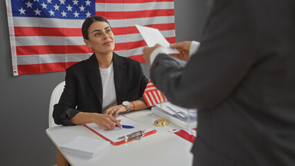 Candidate woman and man in suit indoors with united states flag, discussing papers during electoral...