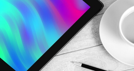 Image of tablet with colorful moving shapes on screen on desk