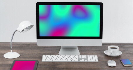 Image of technological devices with colorful moving shapes on screen on desk