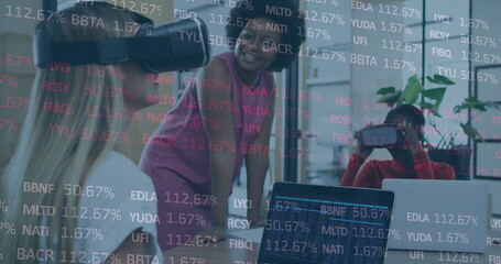 Image of stock market data processing over two diverse women wearing vr headset at office