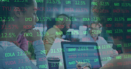 Image of stock market data processing over two diverse women discussing over a laptop at office