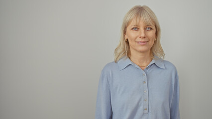 A portrait of a smiling, blonde woman wearing a blue shirt against a white background, exuding confidence and beauty.