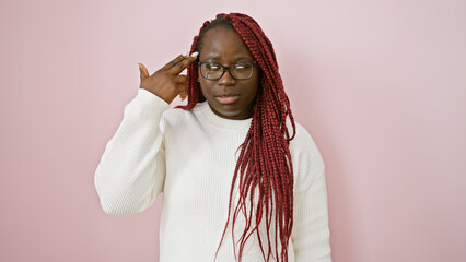 Adult black woman with braids and glasses posing over a pink background, expressing thoughtfulness.