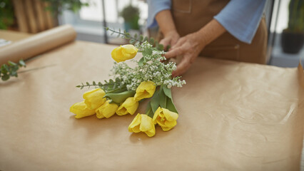 Obraz na płótnie Canvas Mature woman arranging yellow tulips in a flower shop interior