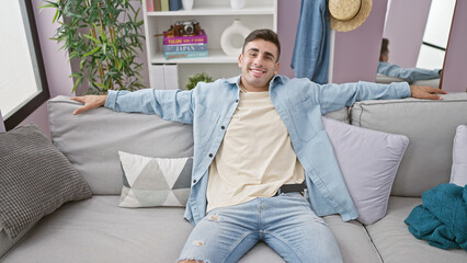 Confident young hispanic man at home, relaxing on the sofa with a positive expression and radiant...