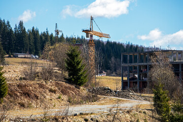 construction crane against the backdrop of an unworthy house on a sunny day. Real estate and...