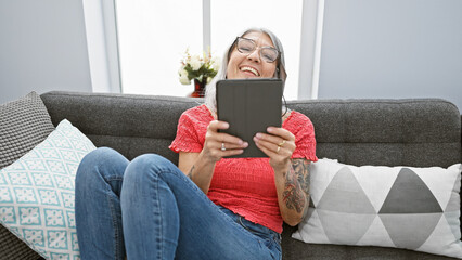 Confident middle age woman enjoying tech-life! at home, a smiling grey-haired beauty sitting...