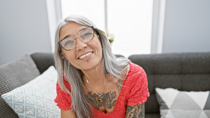 Radiant middle age woman, grey-haired and confident, joyfully smiling while sitting comfortably on...