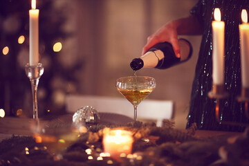 Crop woman pouring champagne during Christmas celebration
