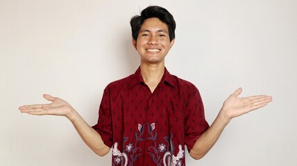 Handsome Asian young man dressed in batik posing with open arms and looking at palms