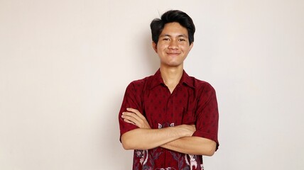 Handsome young Asian man dressed in batik posing crossed arms