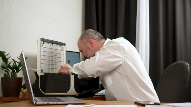 Business stress, irritability, unstable mental state. Man angrily pounds on broken printer, rips off cover and throws it away. Businessman experiences frustration at work, overworked by tasks. Mature