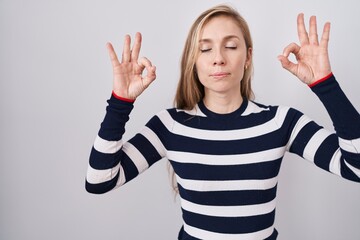 Young caucasian woman wearing casual navy sweater relax and smiling with eyes closed doing meditation gesture with fingers. yoga concept.