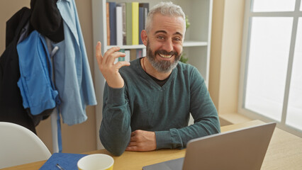 A smiling bearded man gesturing during a video call in a cozy home office setting.