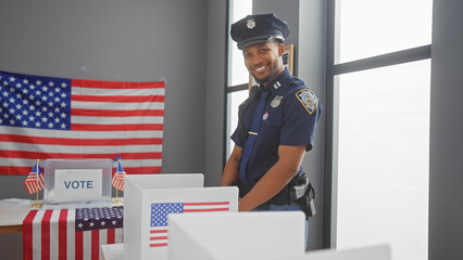 African american policeman smiling in a voting center with us flags.