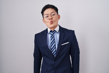 Young asian man wearing business suit and tie making fish face with lips, crazy and comical gesture. funny expression.