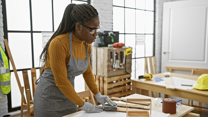 African american woman with braids working in a carpentry workshop indoors
