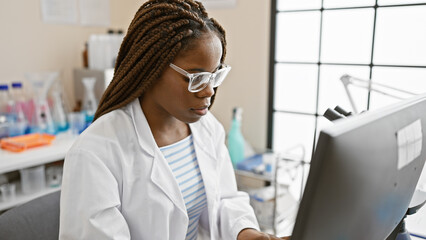 A focused african american woman with braids working in a laboratory, indoors.