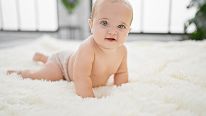 Adorable baby lying in comfort on the bed of a cozy bedroom inside a cute little apartment,...