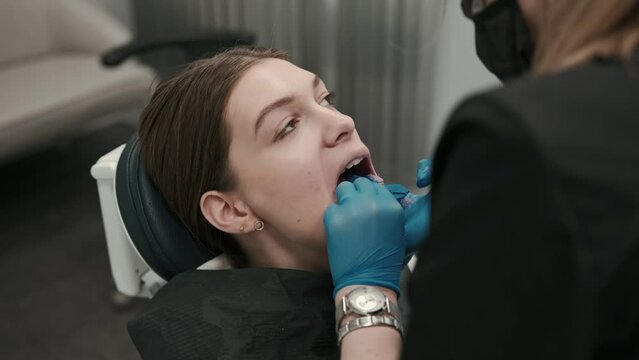 The orthodontist using dental impression tray on woman teeth. Dental spatula with print for dental implant.