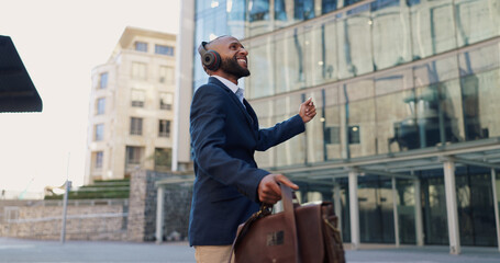 Business man, dancing and headphones in city with smile, steps and spin with bag for commute by...