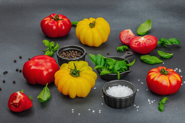 Colorful Heirloom tomato harvest. Ripe ribbed vegetables with fresh basil leaves. Wooden background
