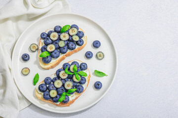 Fresh bread sandwiches with sweet blueberries, cream cheese and basil leaves. Good morning concept