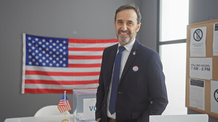Mature man with beard stands proud in suit with 'i voted' sticker, american flag backdrop, at...