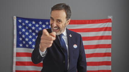 Smiling bearded man in suit pointing with american flag behind, symbolizing leadership and...