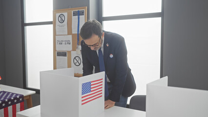 Middle-aged man with beard voting at american electoral polling station - obrazy, fototapety, plakaty