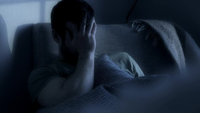 Man in foreground sitting in an armchair in the gloomy twilight. Depressive status