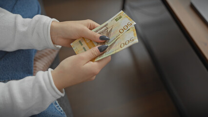 Caucasian woman counting norwegian currency indoors, depicting finance, home budgeting and economy.