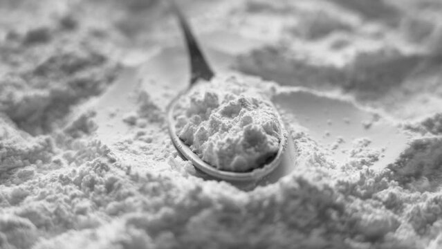 Magnesium oxide mineral supplement in a metallic measuring spoon close up. Rotation