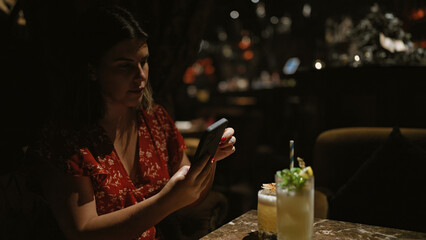 Beautiful hispanic woman captures fun nightlife moment, joyously tableside holding tropical...