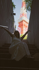 Fototapeta premium Beautiful hispanic woman in glasses perched on stairs, a portrait of urban modernity at tokyo's famous tower spot
