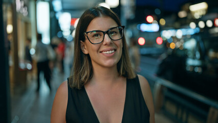 Laughing out loud, a confident beautiful hispanic woman wearing glasses stands joyfully on a street...