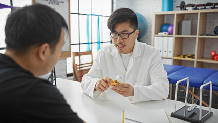 Doctor explaining medication to a male patient in a clinic office with medical equipment in the background.