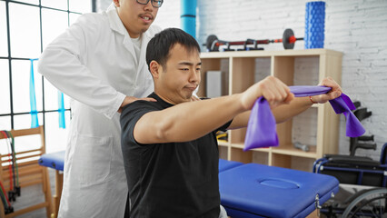 Man undergoing shoulder rehabilitation with a therapist assisting in a bright physiotherapy clinic.