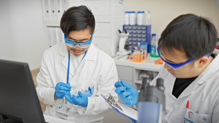 Two men in lab coats working attentively in a scientific laboratory with test tubes and a microscope