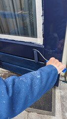 painting a door with blue paint with a roller - 785346963