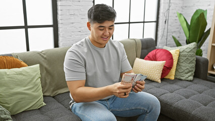 Asian man counting hong kong dollars in a modern indoor living room setting.