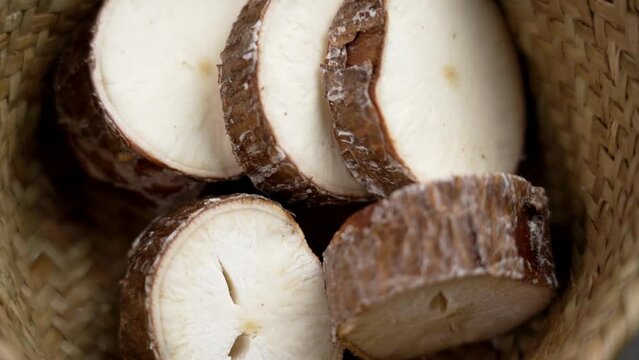 Sliced cassava yucca rhizomes falling into a rustic bowl in slow motion. Healthy vegetable food