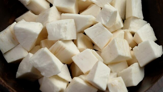 Fresh sliced peeled Cassava roots in wooden bowl. Raw Yucca ingredient. Starchy Manioc slices. Rotation